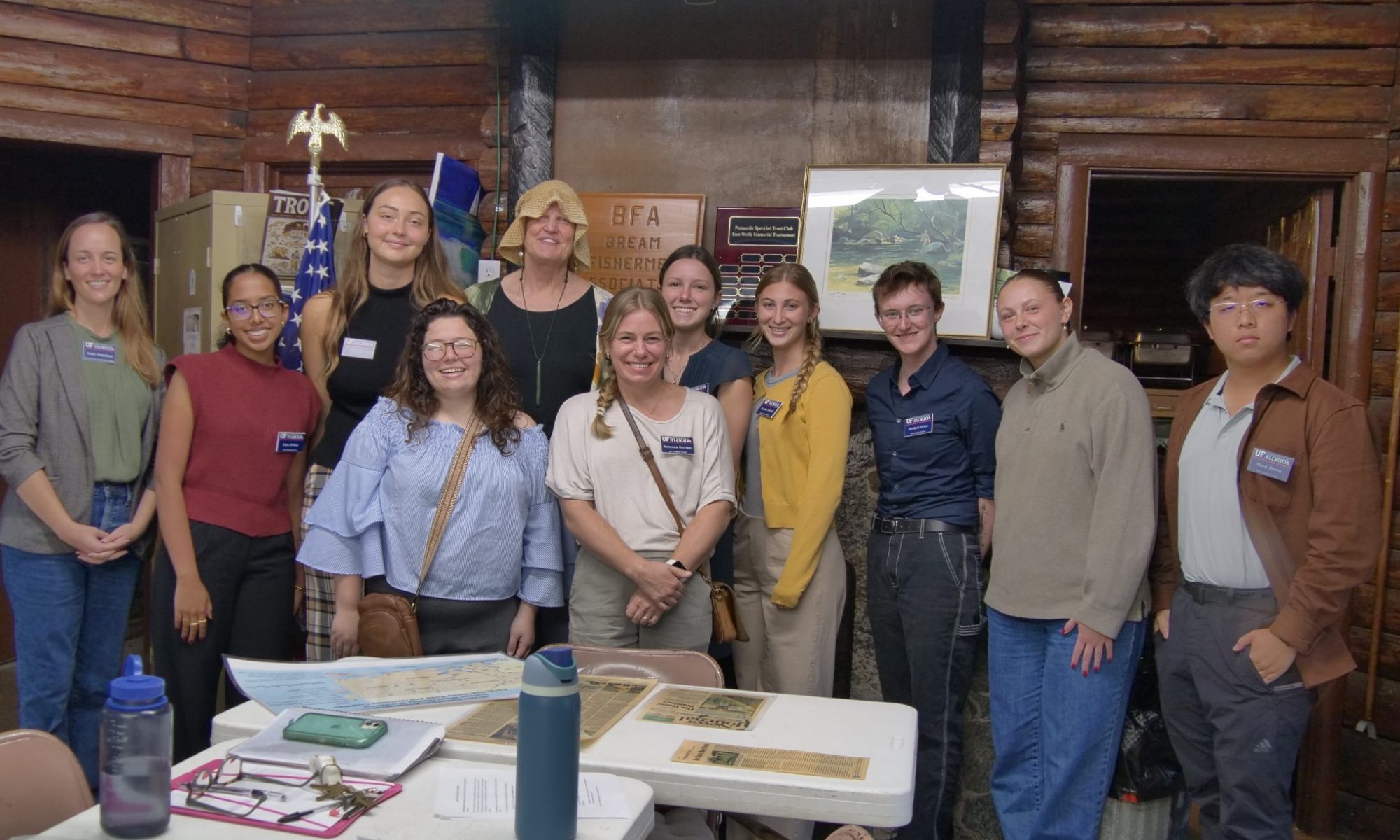 A photo of a group of student researchers posing with narrator Barbara Albrecht inside the Bream Fishermen Association building in Pensacola, Florida.